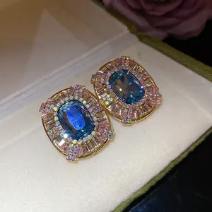 Dettaglio ravvicinato di orecchini vintage ovali con gemma blu e bordo di diamanti incastonati