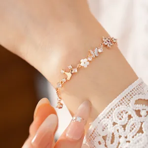 Close-up of rose gold bracelet with zircon, mother-of-pearl butterfly and flower motifs