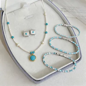 Elegante set di gioielli in perle e turchese con collana, orecchini e braccialetti.