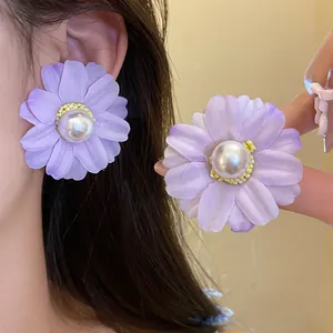 Close-up view of elegant purple fabric flower stud earrings with white pearl centers
