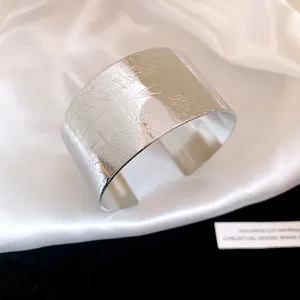 Close-up of retro silver wide cuff bracelet with detailed floral engraving and glossy finish