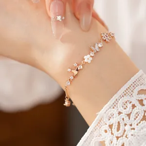 Macro shot of a rose gold bracelet with shell butterfly and flower charms set with zircons