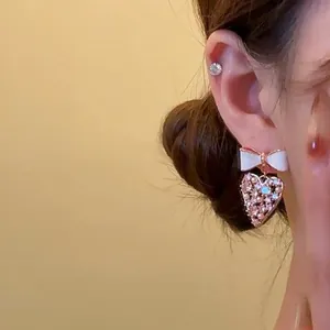 Gros plan de boucles d'oreilles élégantes nœud et cœur avec cristaux roses pour un look doux