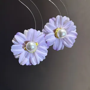 Macro detail view of vintage purple fabric flower earrings featuring a glossy pearl center
