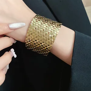 Detailed close-up of a wide vintage gold woven cuff bracelet styled on a woman's wrist