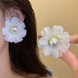 Elegant white fabric flower earrings with a pearl center on silver needles detail view.