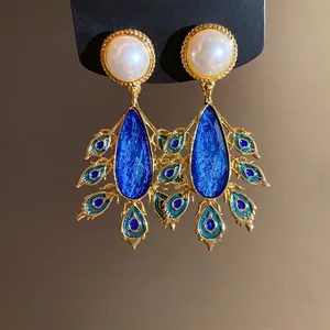 Elegant vintage style teardrop pearl earrings with blue peacock feather design in gold tone