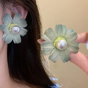 Close-up detail of a mint green fabric flower earring with a large pearl center