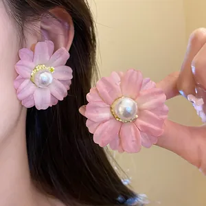 Close-up of pink fabric flower stud earrings with pearl center on model.