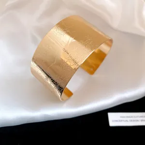 Close-up of a vintage gold cuff bracelet featuring intricate floral pattern engravings
