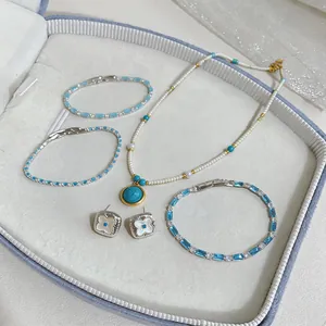 Vista dettagliata di un set di gioielli eleganti con perle turchesi e orecchini a fiore in box.