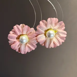 Macro detail view of elegant pink fabric flower stud earrings with a central white pearl