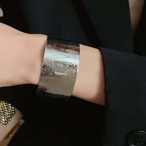 Detailed macro view of a vintage wide silver pleated open cuff bracelet with floral texture