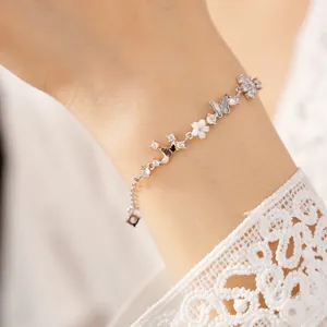 Close-up of elegant silver bracelet with butterfly and crown charms on wrist