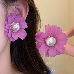 Detail shot of elegant purple fabric flower stud earrings with a large white pearl center