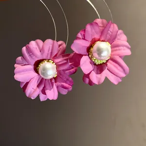 Detailed macro view of elegant pink fabric flower earrings featuring a pearl center