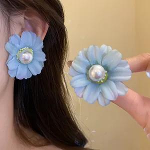 Detailed view of blue fabric flower earrings with central pearl and silver needle