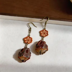 Detailed macro view of vintage ethnic ear hook earrings featuring wooden flower and resin pendant