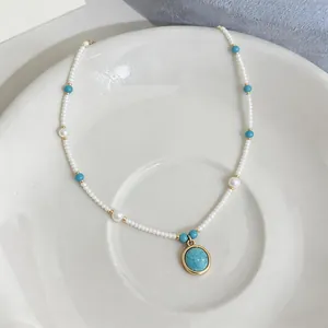 Dettaglio elegante di una collana di perle bianche con ciondolo in pietra turchese blu