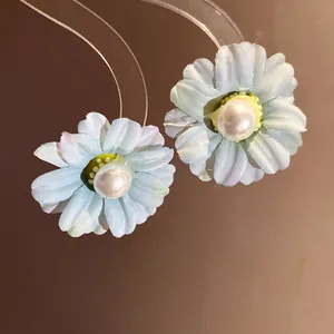 Detail view of light blue fabric daisy flower earrings with elegant white pearl center