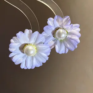 Close-up of lavender fabric flower earrings featuring a central white pearl detail.
