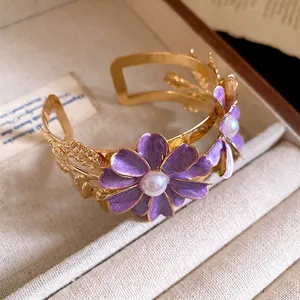 Elegant gold double-layered cuff bracelet featuring purple enamel flowers with pearls.