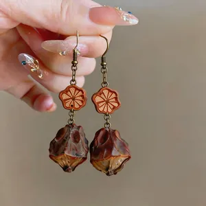 Detail view of vintage ethnic style earrings with natural seed pods and carved wooden flowers