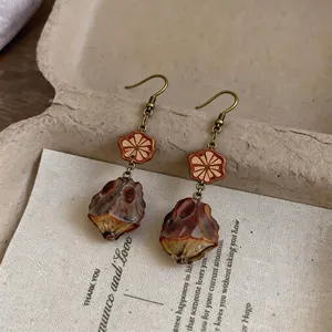 Close-up of vintage ethnic drop earrings with carved wood flower and seed pod detail