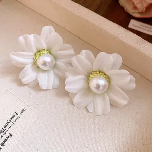 Close-up of elegant white fabric flower stud earrings with a central faux pearl.