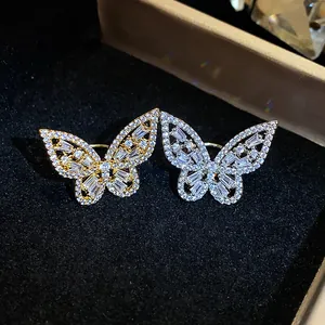 Macro view of sparkling zircon butterfly ear clips in polished gold and silver finishes