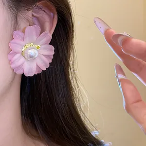 Macro detail view of pink fabric flower stud earring with central pearl on model