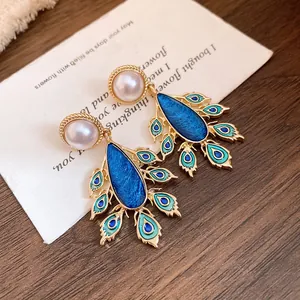 Detailed view of vintage peacock feather drop earrings featuring pearls and blue enamel