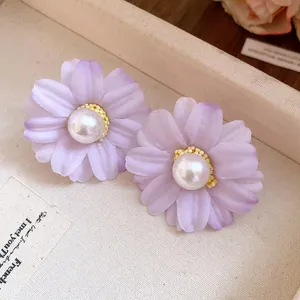 Close-up of purple fabric flower stud earrings with elegant pearl centers