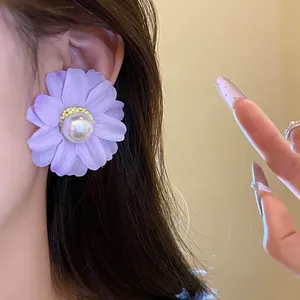 Close-up of elegant purple fabric flower stud earring with a pearl center on a model's ear