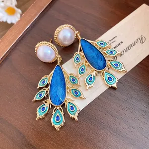 Close-up of vintage pearl earrings with blue peacock feather water drop pendants