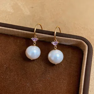 Vue détaillée de boucles d'oreilles perles avec gemmes violettes et crochets dorés