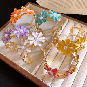 Detailed view of colorful oil-dripped flower cuff bracelets with pearl centers