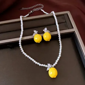 Elegant pearl necklace and yellow lemon resin earrings set with sparkling zircon leaf details
