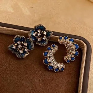 Vintage dark blue enamel flower and rhinestone stud earrings on luxury brown tray