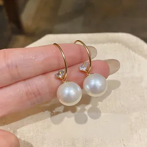 Gros plan sur d'élégantes boucles d'oreilles pendantes en perles au style français chic.