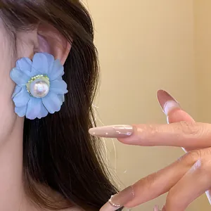 Close-up detail of vintage blue fabric flower stud earring with pearl on model ear