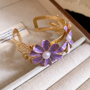 Detail shot of purple enamel flower bracelet with pearl center in gold finish