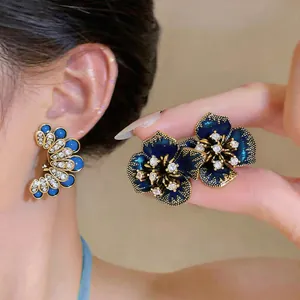 Detail shot of dark blue floral stud earrings with sparkling rhinestones and silver pins.