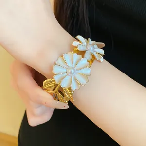 Detailed view of an elegant gold flower bangle with white enamel petals and central pearls