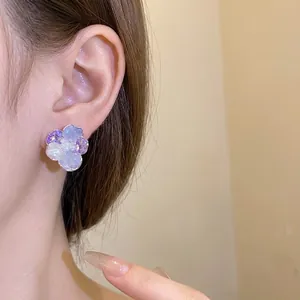 Elegant purple floral stud earrings with cubic zirconia and pearls shown on model ear
