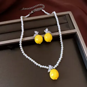 Detailed view of the resin lemon pendant and matching earrings on a pearl necklace