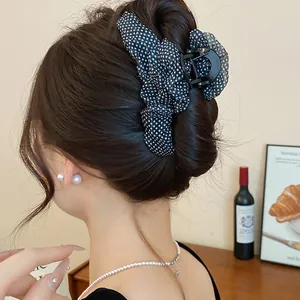 Detailansicht einer Haarklammer mit schwarzen Polka-Dots und Netzstoff auf einem Haardutt
