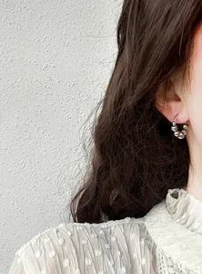 Macro close-up of minimalist silver metallic beaded hoop earrings on an Asian model ear