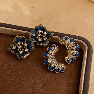 Elegant vintage dark blue flower and rhinestone C-shaped stud earrings on brown velvet