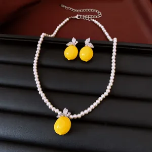 Detailed view of the yellow resin lemon pendant and pearl necklace set with zircons